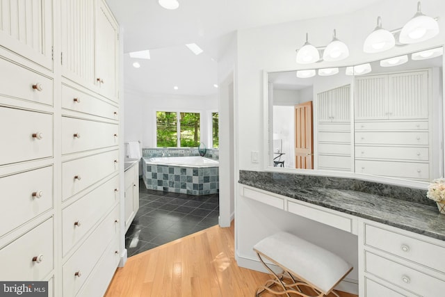 511 Center Hl, Upper Black Eddy, PA 18972 - bathroom featuring a garden tub, wood finished floors, vanity, and a skylight
