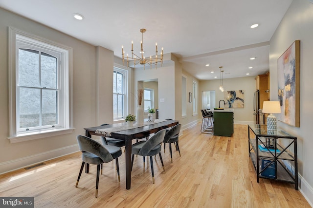 dining area featuring a chandelier, light wood-style floors, baseboards, and recessed lighting