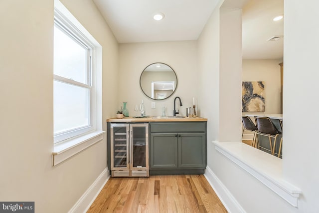 indoor wet bar featuring wine cooler, light wood finished floors, baseboards, and recessed lighting