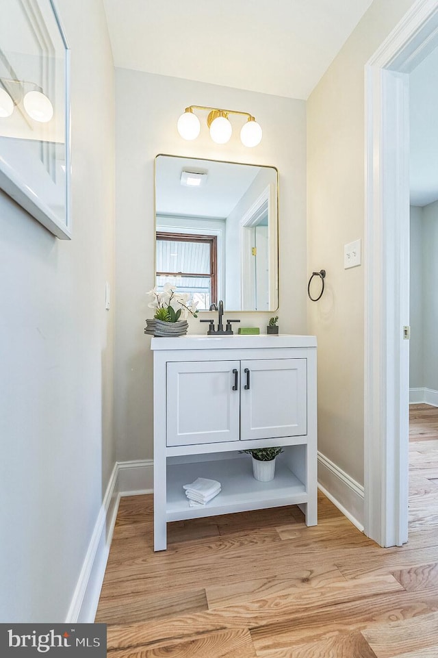 bathroom with baseboards, wood finished floors, and vanity