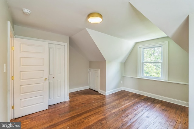 additional living space with hardwood / wood-style flooring, baseboards, and vaulted ceiling