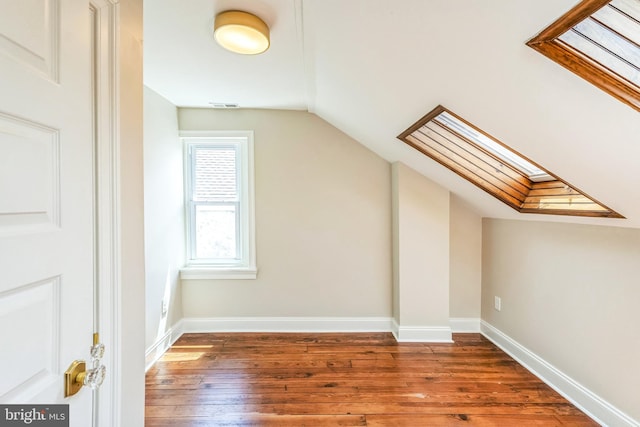 bonus room featuring a skylight, lofted ceiling, hardwood / wood-style flooring, and baseboards