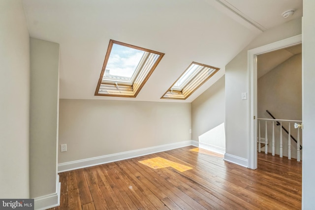 bonus room featuring lofted ceiling, a skylight, hardwood / wood-style floors, and baseboards