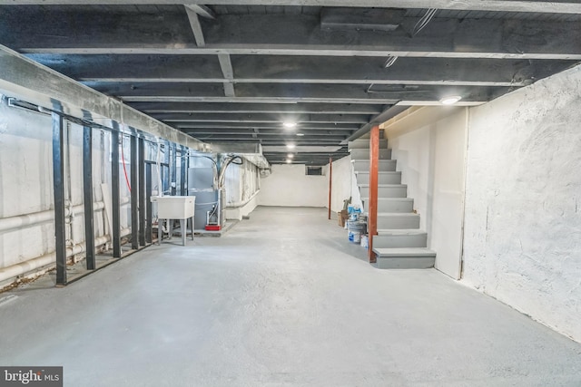 unfinished below grade area with stairs, a sink, and heating unit