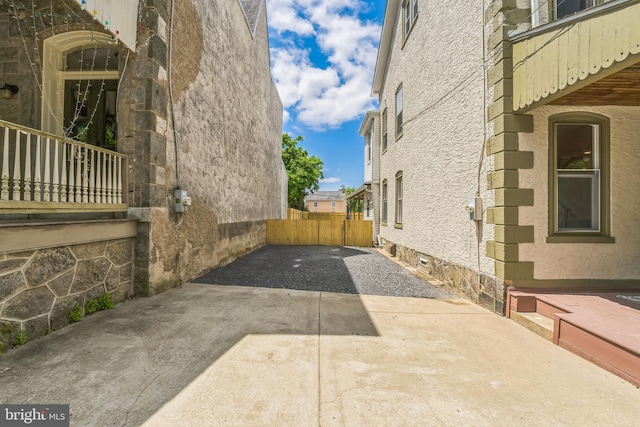 view of property exterior featuring driveway, a patio area, and stone siding