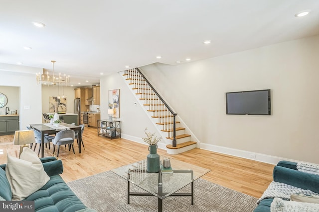 living area with stairs, a chandelier, baseboards, light wood-style flooring, and recessed lighting