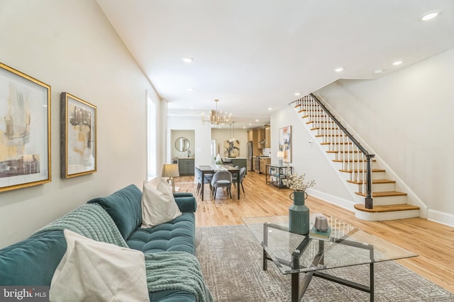 living area with stairs, a chandelier, light wood-style floors, baseboards, and recessed lighting