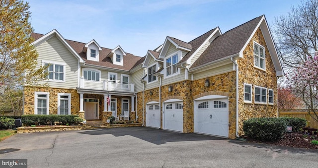 2017 Woodford Rd, Vienna, VA 22182 - view of front of property featuring stone siding, driveway, an attached garage, a balcony, and covered porch