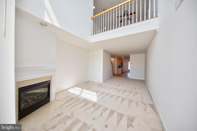 33 Owens Landing Ct Unit 33C, Perryville, MD 21903 - unfurnished living room featuring a towering ceiling, a glass covered fireplace, carpet, and baseboards
