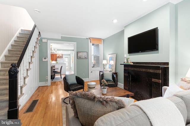 836 N 25th St, Philadelphia, PA 19130 - living room featuring stairs, light wood-style floors, a chandelier, crown molding, and a premium fireplace