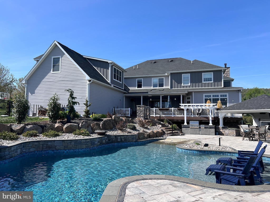 outdoor pool with stairs, a patio, and exterior kitchen