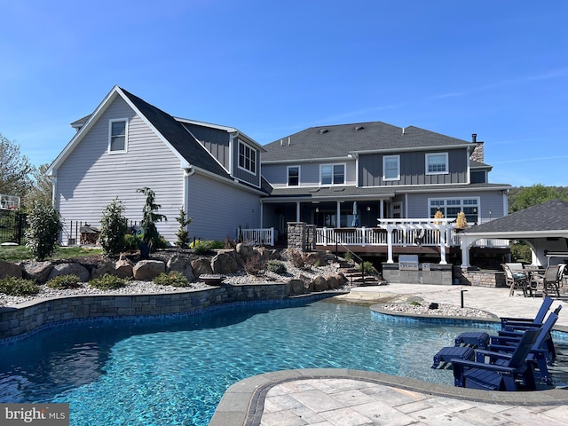 outdoor pool with stairs, a patio, and exterior kitchen