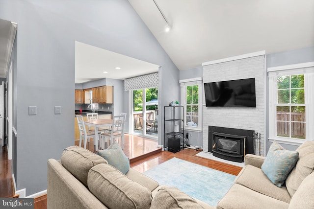 12125 Gatewater Dr, Potomac, MD 20854 - living area with wood finished floors, rail lighting, baseboards, high vaulted ceiling, and a brick fireplace