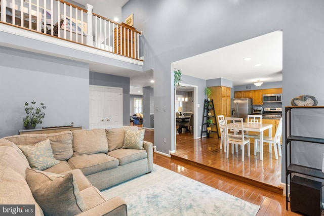 12125 Gatewater Dr, Potomac, MD 20854 - living room featuring light wood-style floors, a towering ceiling, and baseboards