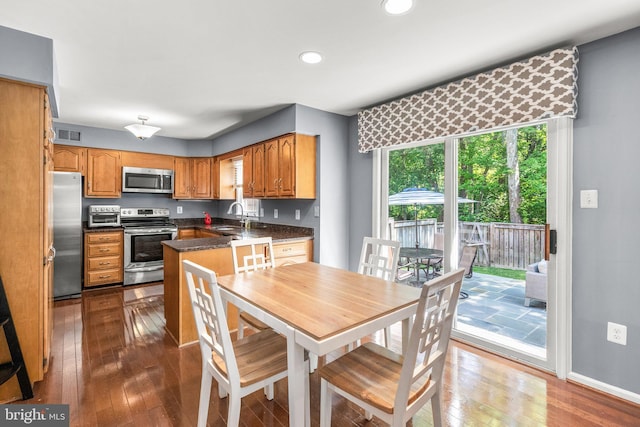 12125 Gatewater Dr, Potomac, MD 20854 - kitchen featuring appliances with stainless steel finishes, a sink, dark countertops, dark wood-style floors, and brown cabinetry