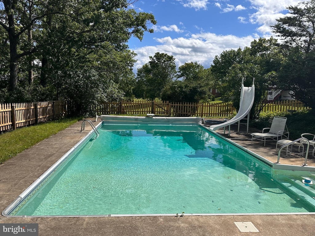 1103 Waugh Rd, Berkeley Springs, WV 25411 - view of pool with a water slide, a fenced backyard, view of scattered trees, and a patio