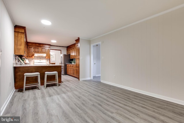 5183 Silver Run Ln, Salisbury, MD 21801 - kitchen with freestanding refrigerator, under cabinet range hood, light wood finished floors, a peninsula, and ornamental molding
