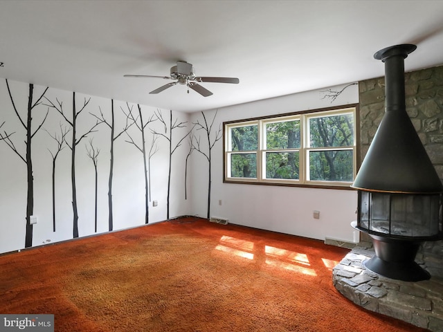 1700 Mcdowell Rd, Greencastle, PA 17225 - unfurnished living room featuring a wood stove, carpet flooring, a ceiling fan, and baseboards