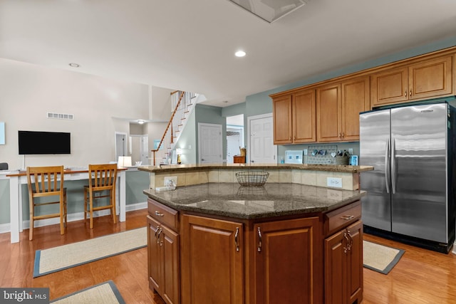 8 Warwick Ct, Newtown, PA 18940 - kitchen with freestanding refrigerator, light wood finished floors, brown cabinetry, dark stone counters, and recessed lighting