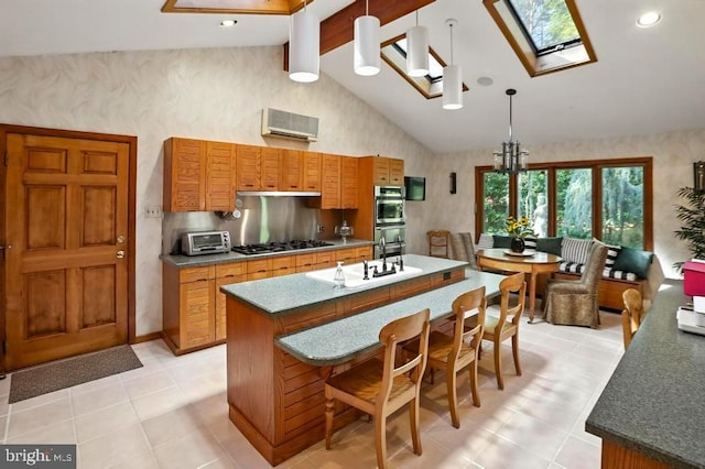 2361 Welsh Rd, Mohnton, PA 19540 - kitchen featuring gas stovetop, brown cabinets, a skylight, wallpapered walls, and a center island with sink