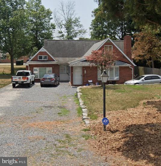 107 Main Ave SW, Glen Burnie, MD 21061 - view of front facade with gravel driveway, a chimney, brick siding, and a front lawn