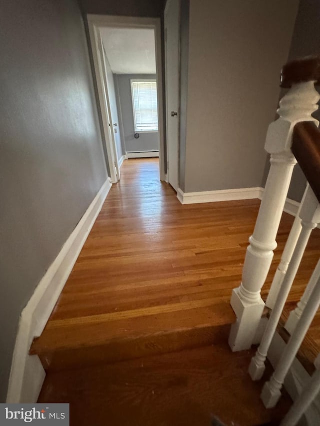 hall featuring a baseboard radiator, light wood-style floors, and baseboards