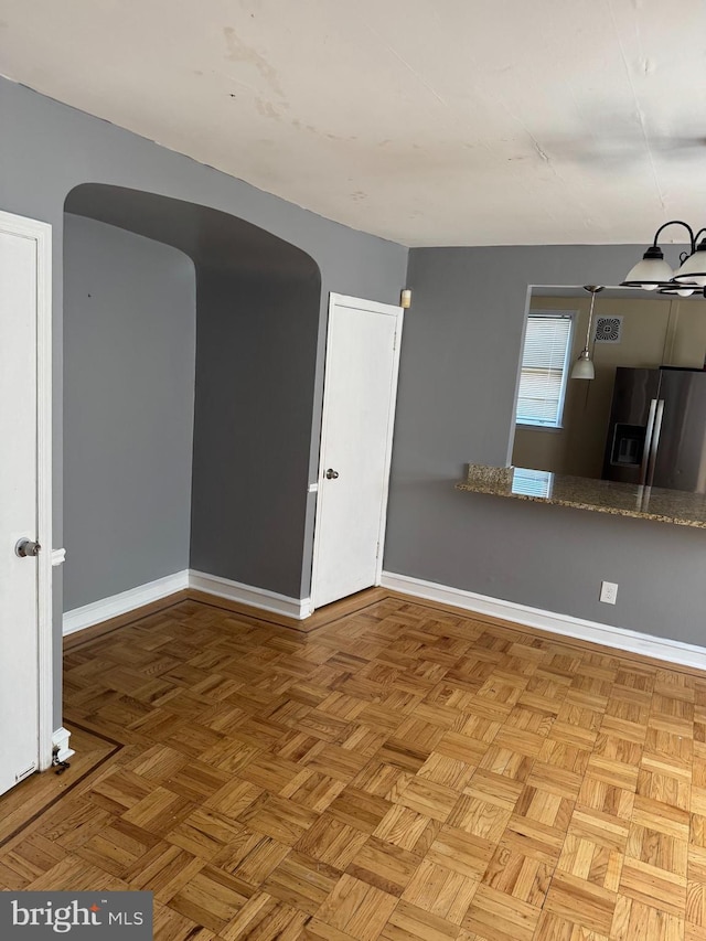 spare room featuring arched walkways and baseboards