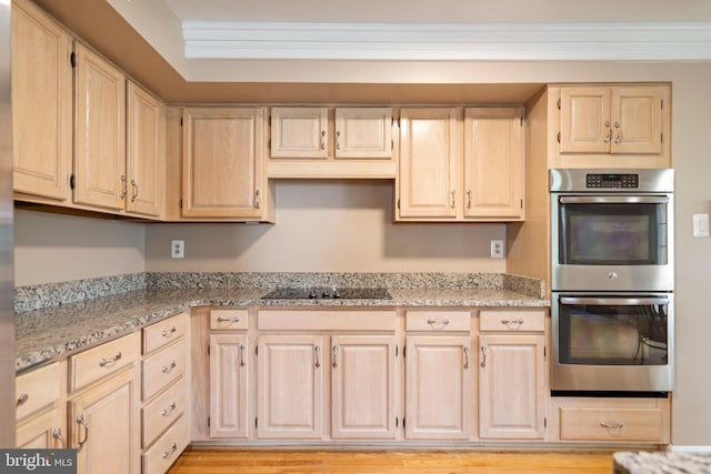 20245 Ordinary Pl, Ashburn, VA 20147 - kitchen with stainless steel double oven, black electric stovetop, light brown cabinets, light stone counters, and light wood-style floors