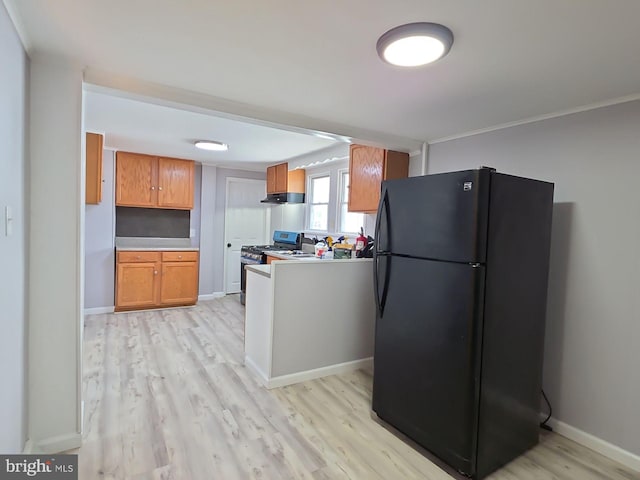 131 Vine St, Bridgeton, NJ 08302 - kitchen featuring freestanding refrigerator, stainless steel range with gas stovetop, under cabinet range hood, light wood finished floors, and brown cabinets
