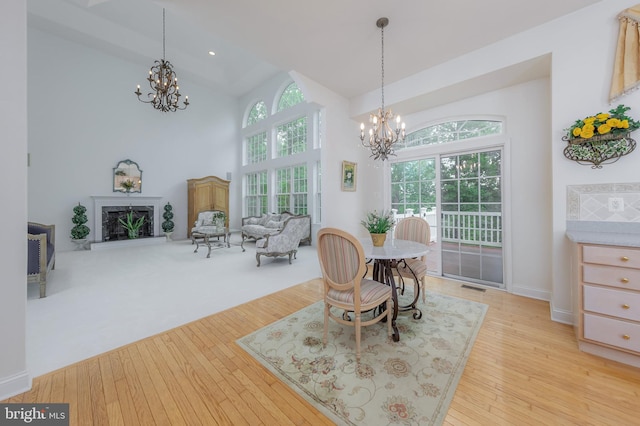 144 Cedar Ct, Woolwich Twp, NJ 08085 - dining room featuring a chandelier, a towering ceiling, light wood finished floors, and a fireplace