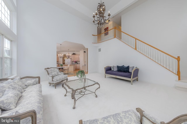 144 Cedar Ct, Woolwich Twp, NJ 08085 - living area with a chandelier, stairway, a high ceiling, carpet flooring, and arched walkways