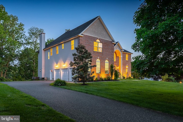 144 Cedar Ct, Woolwich Twp, NJ 08085 - view of front of home featuring a chimney, an attached garage, asphalt driveway, a front lawn, and brick siding