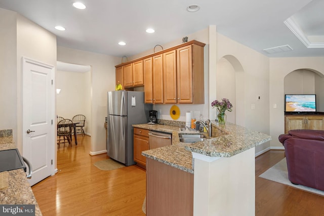 35206 Seagrass Plantation Ln, Dagsboro, DE 19939 - kitchen featuring a sink, stainless steel appliances, light wood-style floors, a peninsula, and light stone counters
