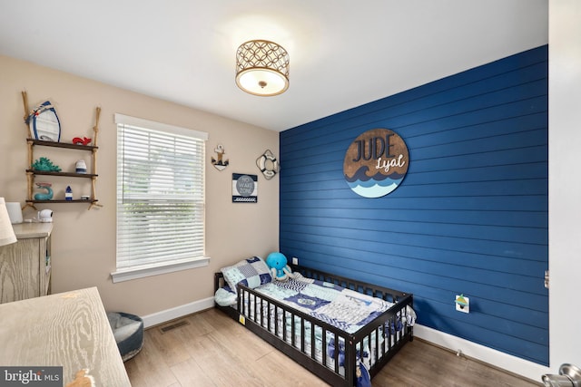 10744 Hinton Way, Manassas, VA 20112 - bedroom with an accent wall, baseboards, wood finished floors, and wooden walls