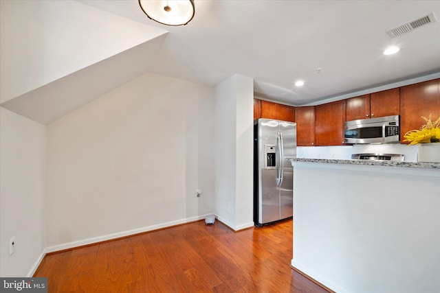 6124 Aster Haven Cir, Haymarket, VA 20169 - kitchen featuring stainless steel appliances, wood finished floors, light stone counters, brown cabinets, and baseboards