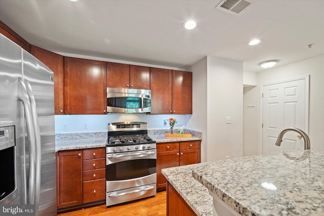 6124 Aster Haven Cir, Haymarket, VA 20169 - kitchen featuring appliances with stainless steel finishes, light wood-style flooring, light stone countertops, and recessed lighting