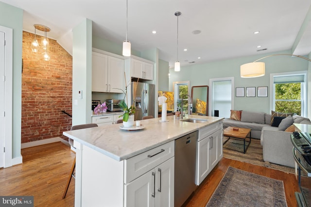 158 Bryant St NW Unit 2, Washington, DC 20001 - kitchen featuring appliances with stainless steel finishes, brick wall, open floor plan, white cabinets, and wood finished floors