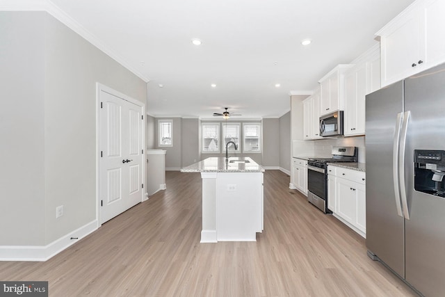 kitchen with appliances with stainless steel finishes, a sink, baseboards, ornamental molding, and white cabinets