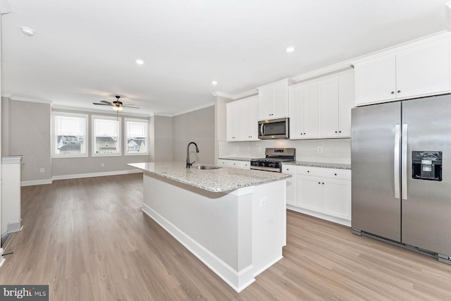 kitchen with stainless steel appliances, a sink, light wood-style floors, crown molding, and white cabinets