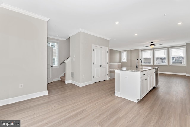 kitchen featuring a sink, baseboards, crown molding, light wood-style flooring, and white cabinets