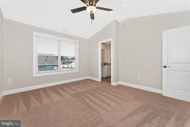 unfurnished bedroom with carpet floors, vaulted ceiling, baseboards, connected bathroom, and ceiling fan