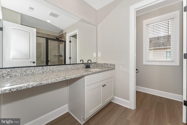 bathroom featuring wood finished floors, a stall shower, vanity, and baseboards