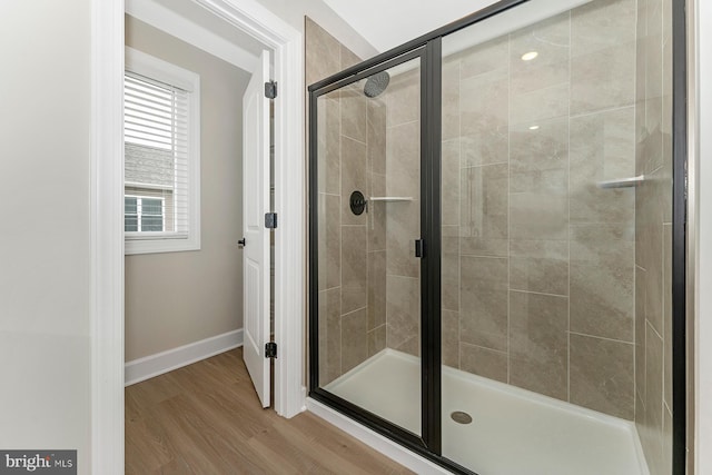 bathroom with a stall shower, wood finished floors, and baseboards