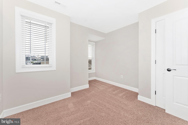 empty room featuring carpet, healthy amount of natural light, and baseboards