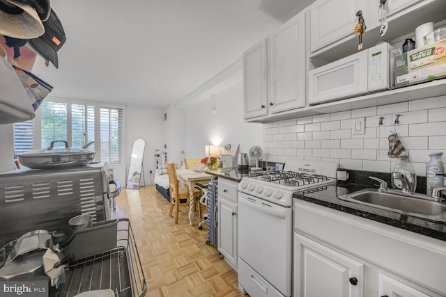 950 25th St NW Unit 301N, Washington, DC 20037 - kitchen featuring white gas range, a sink, decorative backsplash, and white cabinetry
