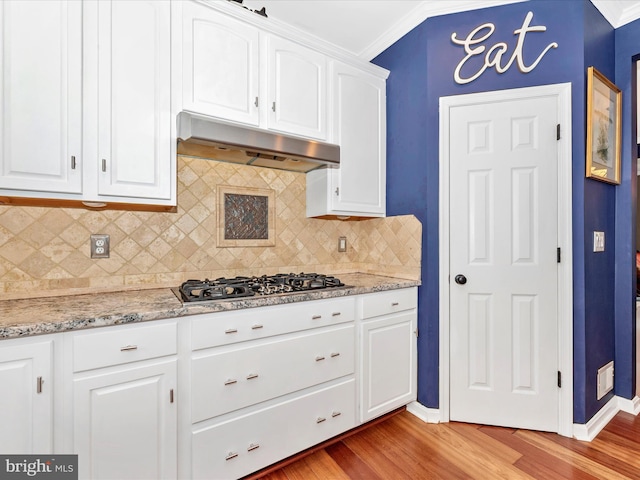 2619 Washington Way, Manchester, MD 21102 - kitchen with under cabinet range hood, stainless steel gas stovetop, light wood-style floors, white cabinetry, and crown molding