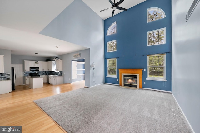 19 Pear Tree Pl, Sewell, NJ 08080 - unfurnished living room featuring ceiling fan, a fireplace with flush hearth, a high ceiling, baseboards, and a chandelier