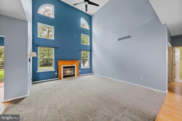 19 Pear Tree Pl, Sewell, NJ 08080 - unfurnished living room with a ceiling fan, a high ceiling, a fireplace with flush hearth, baseboards, and wood finished floors