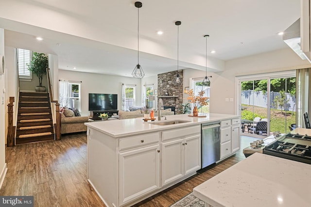 6023 Charles Henry Pl, Hanover, MD 21076 - kitchen with a sink, stainless steel dishwasher, a stone fireplace, a kitchen island with sink, and dark wood-style floors