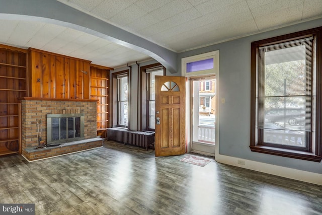 346 Main St, Denver, PA 17517 - unfurnished living room with radiator, arched walkways, wood finished floors, built in features, and a brick fireplace